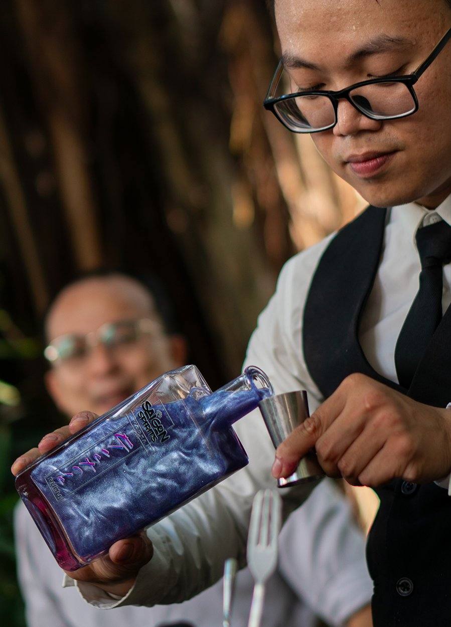 Saigon Spirits Dragonfruit Pink Gin bottle held by woman sunglasses Vietnam lifestyle craft spirits Southeast Asia